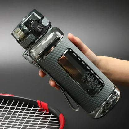 Portable BPA-Free Sports Water Bottle held by a hand with a tennis racket in the background, featuring a sleek design and one-click lid.