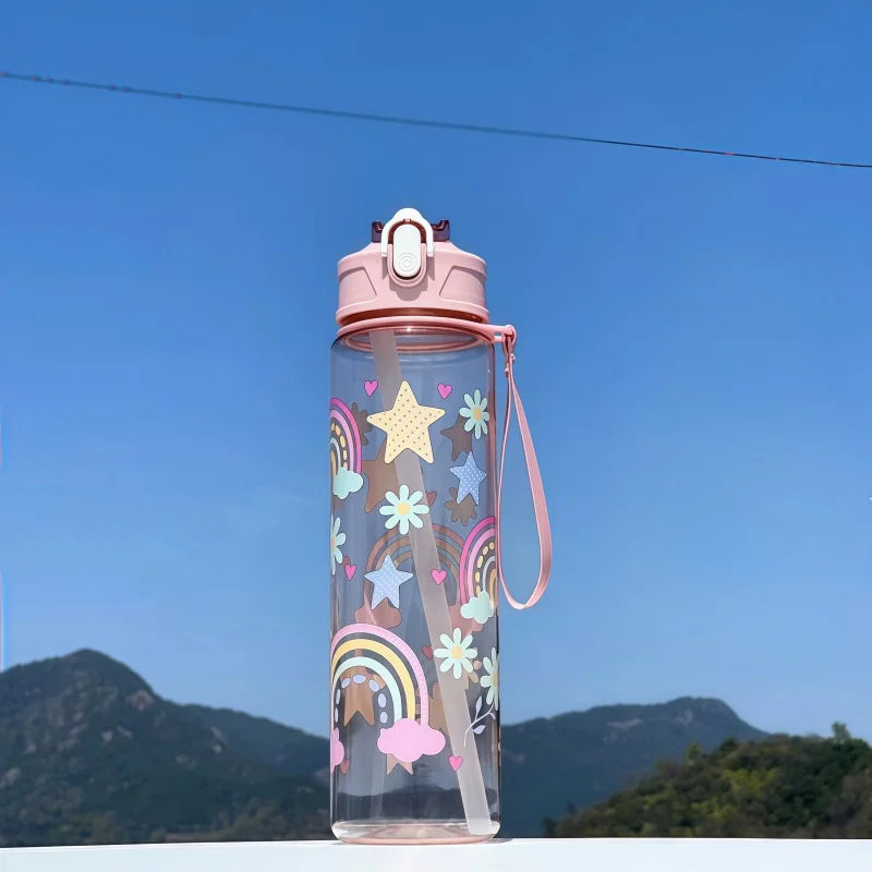 DinoSip Kids Water Bottle featuring a colorful rainbow and star design against a scenic outdoor background.