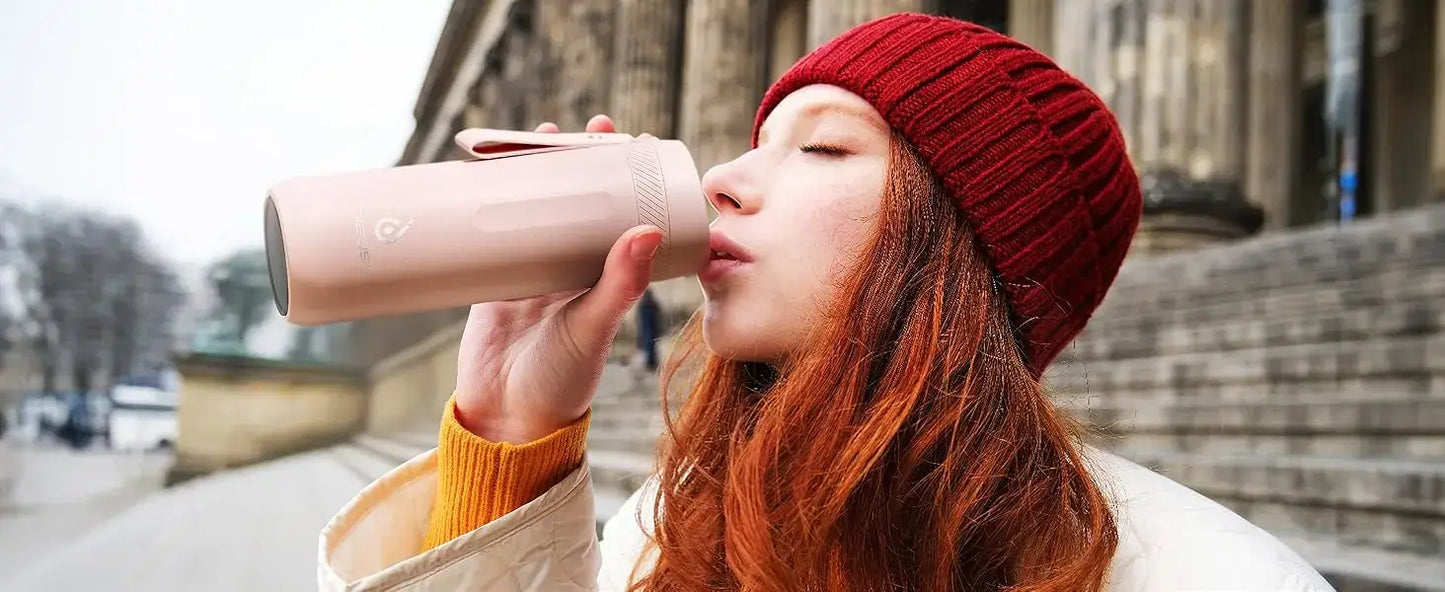 Woman sipping from a PureSip Thermal Bottle outdoors in winter attire.
